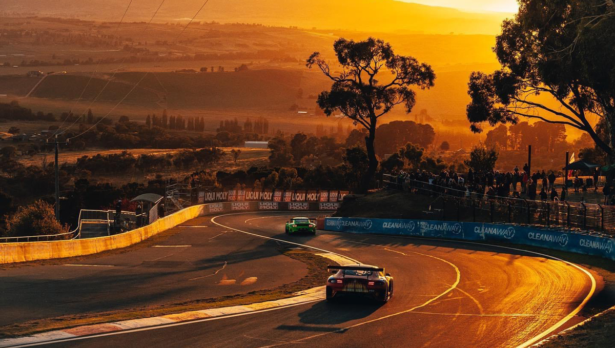 Race cars driving on a road at sunset
