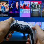 Accedo/ITVX streaming on tv using playstation showing a person holding a gaming controller in front of a TV