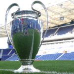 Large silver trophy sitting on a grass football pitch