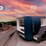 A large square modern building with a rosy sunset sky. The letters CJP are at the top left