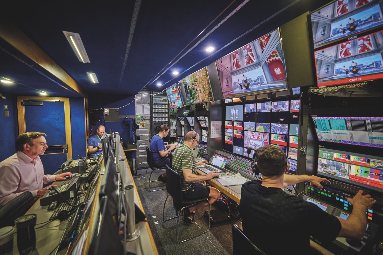 Studio monitoring room with multiple people looking at monitors and screens working