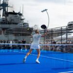 A person playing padel on a blue court in front of a large ship
