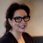 A woman wearing glasses and smiling