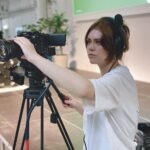 A girl with a headset on holding and using a camera