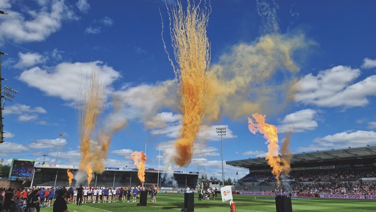 A sports stadium with large orange smoke blasting into the sky