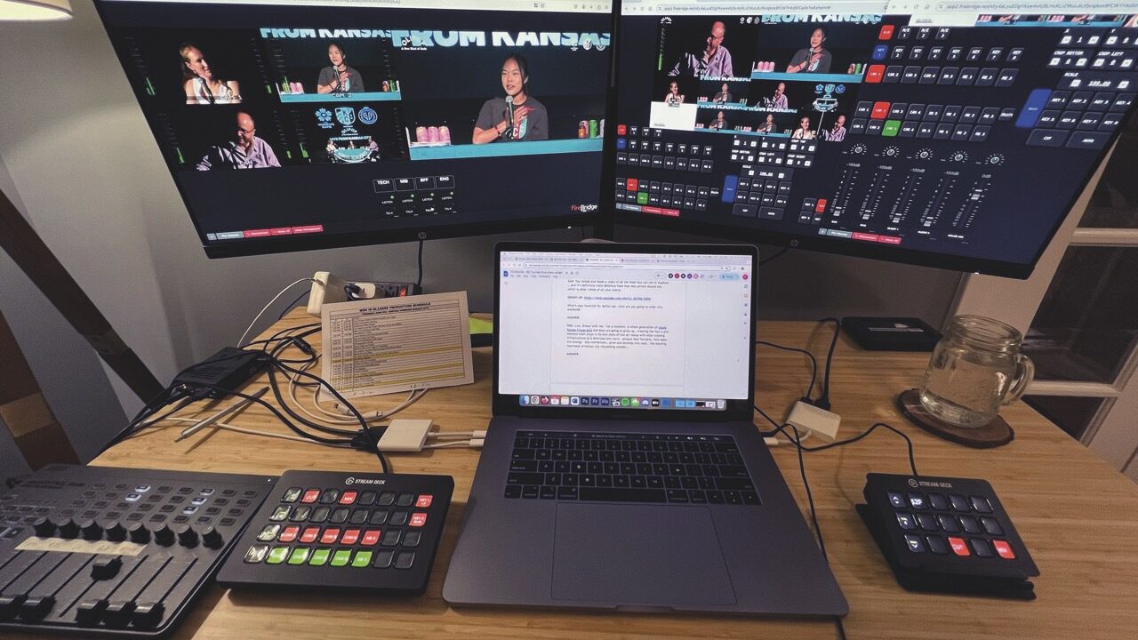 A desk with two monitors, a laptop and mixing desks on top