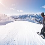A person snowboarding down a sunny snow-covered mountain