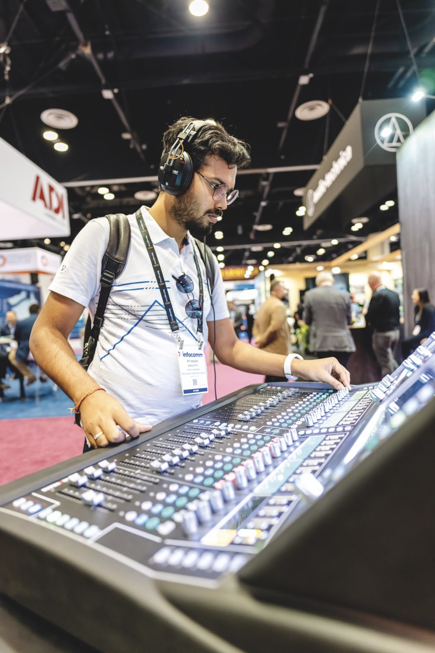 Audio-1 Large A man wearing headphones standing at a mixing desk in a busy conference hall
