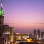 A city skyline at dusk with a skyscraper clock tower