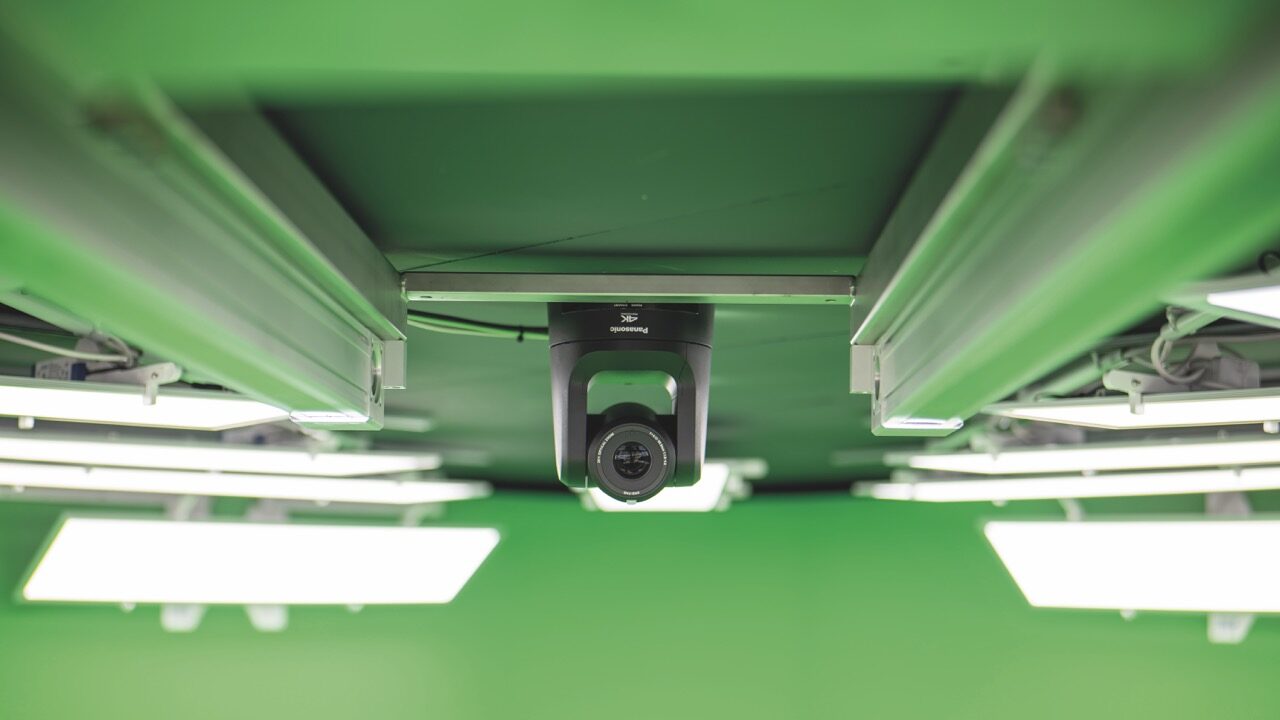 A black camera hangs on a green surface