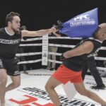 Two men in a boxing ring hitting each other with bags