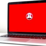 A laptop against on a white surface showing a red error