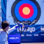 A person doing archery at a World Archery event with a target in the distance