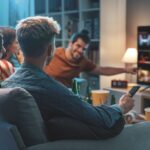A group of friends in gathered in front of the TV in a living room